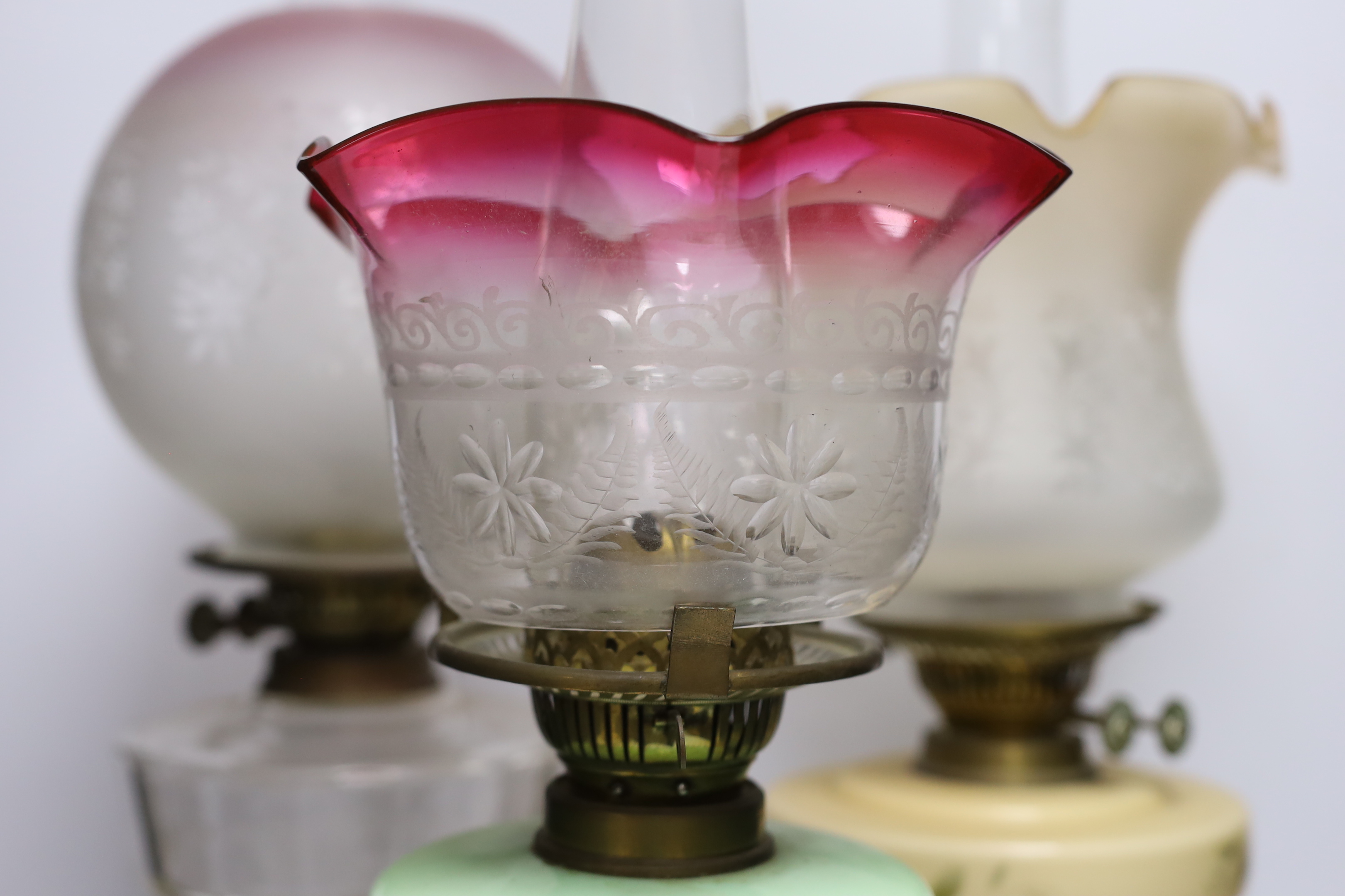 Three glass and brass oil lamps, c.1900, tallest 57cm